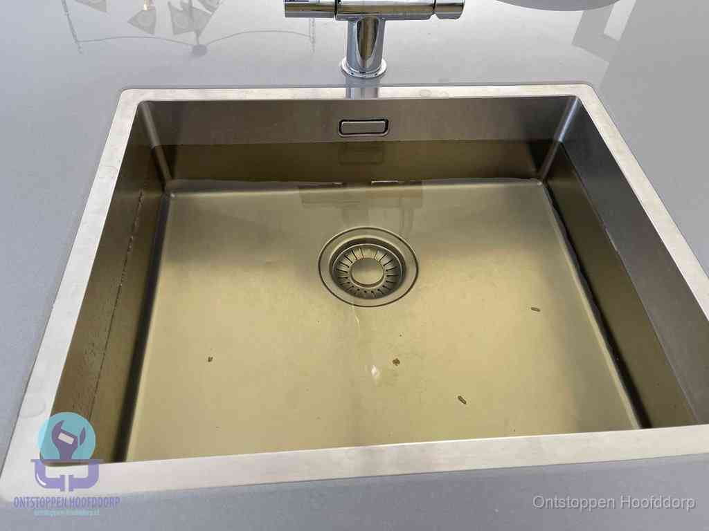 Stilstaand water in een rvs spoelbak dat niet wegloopt, een duidelijk signaal van een gootsteenverstopping in Hoofddorp