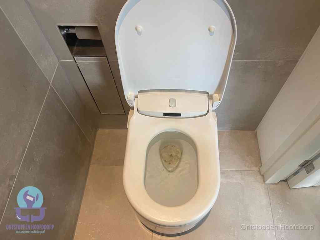 Een wit hangtoilet waarin een prop wc-papier op het water blijft drijven, een duidelijk signaal van een verstopte wc in Hoofddorp