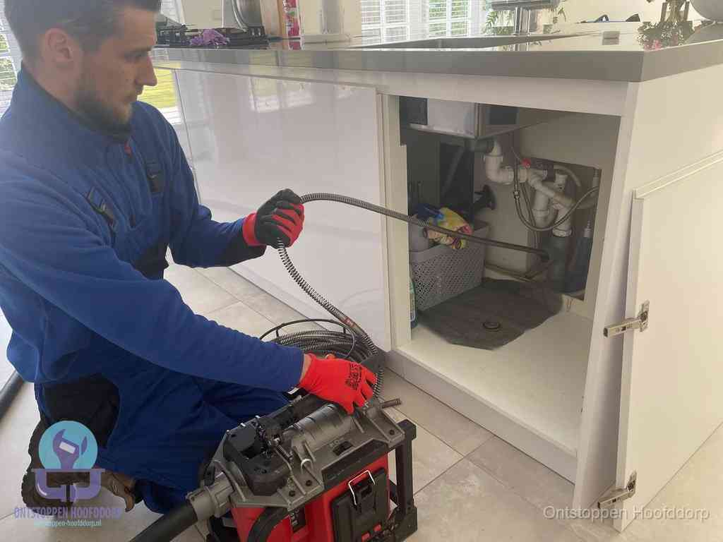 Een monteur reinigt de keukenafvoer grondig met een veermachine om terugkerende gootsteenverstoppingen te voorkomen in Hoofddorp