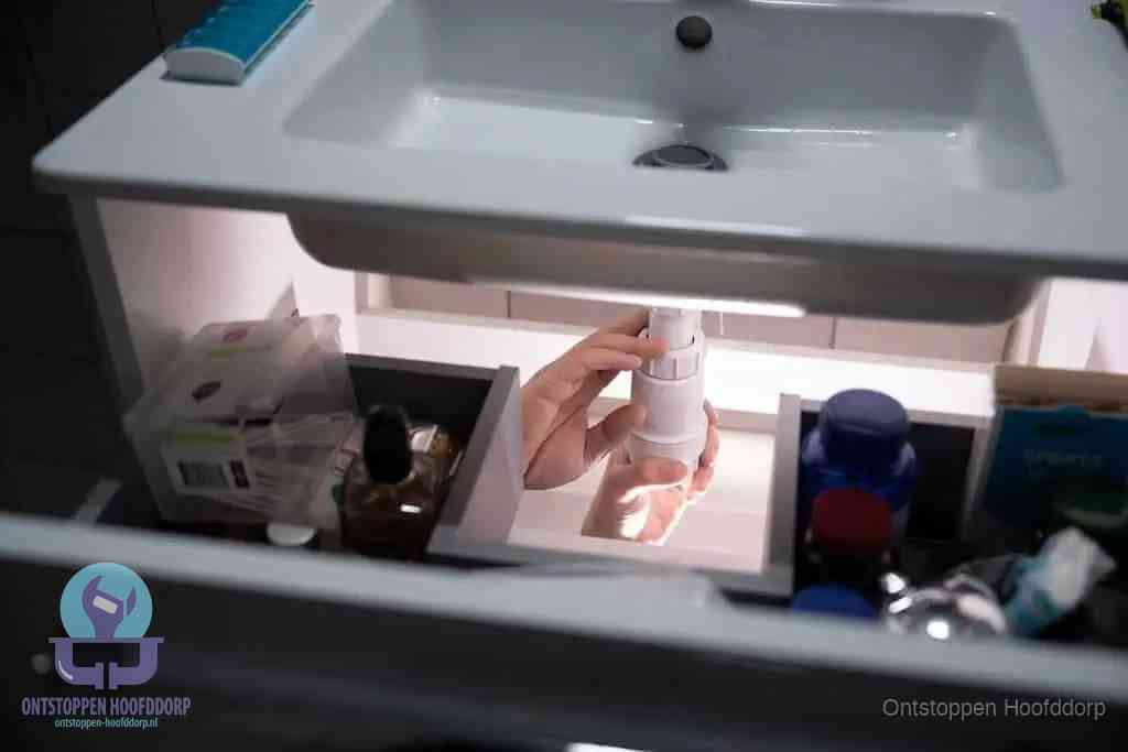 Een pompfles met zeep boven een wastafel in de toiletruimte, de warm water en afwasmiddel-methode om de wc te ontstoppen in Hoofddorp