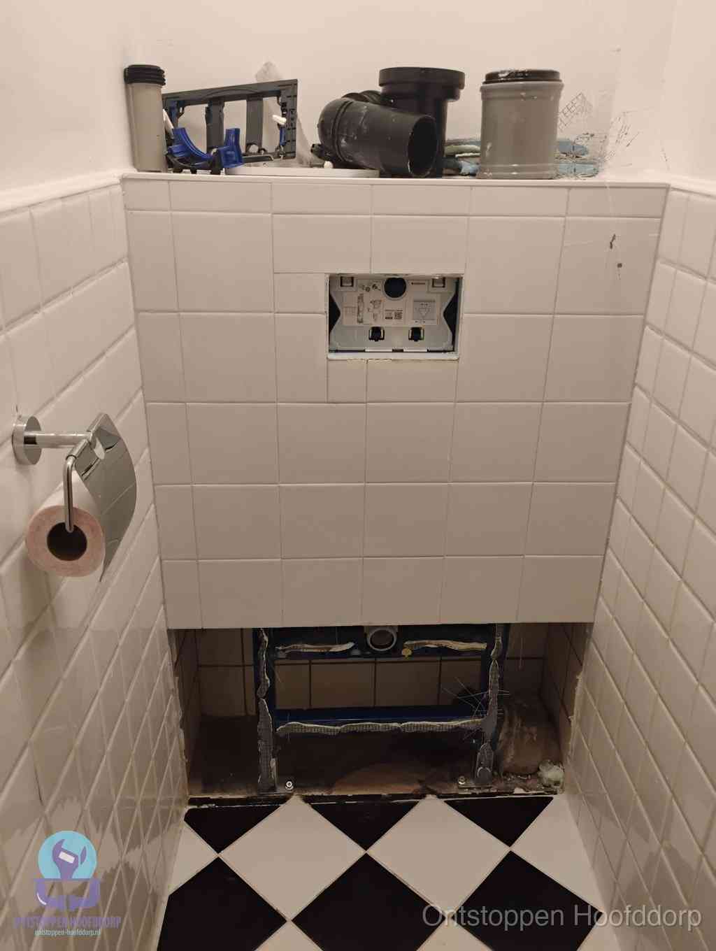 Een toiletruimte waar het hangtoilet en de inbouwreservoir-onderdelen zijn vrijgelegd voor onderhoud, periodiek nazicht voorkomt een wc-verstopping in Hoofddorp