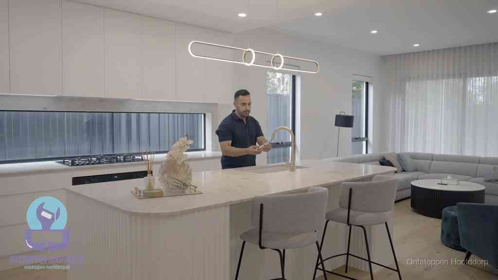 Een bewoner bij de keukenspoelbak die zelf aan de slag gaat met een verstopte gootsteen in Hoofddorp